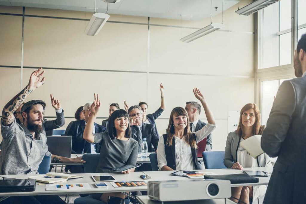 a group of people in a room raising their hands